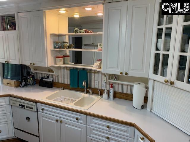 kitchen with sink, white dishwasher, and white cabinetry