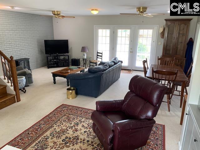 living room with ceiling fan, brick wall, and light colored carpet