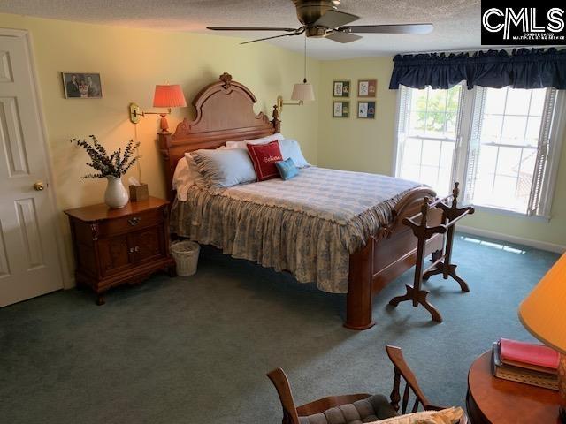 carpeted bedroom with ceiling fan and a textured ceiling