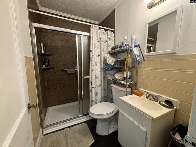 bathroom with vanity, a shower with shower curtain, tile walls, toilet, and a textured ceiling