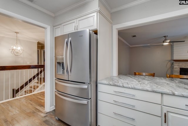 kitchen with crown molding, white cabinetry, light hardwood / wood-style flooring, stainless steel fridge, and ceiling fan with notable chandelier