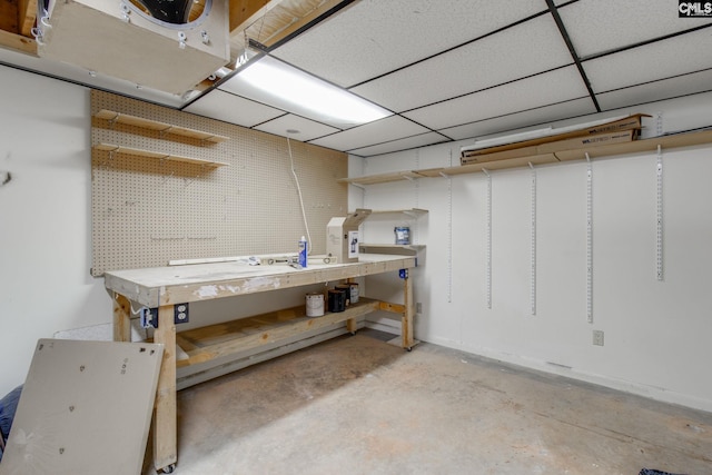 basement featuring a paneled ceiling and a workshop area