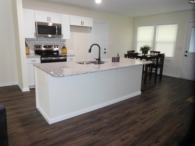 kitchen with sink, light stone counters, stainless steel appliances, a kitchen island with sink, and white cabinets