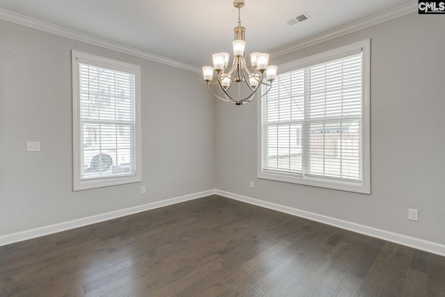 spare room featuring dark hardwood / wood-style floors, ornamental molding, and a notable chandelier