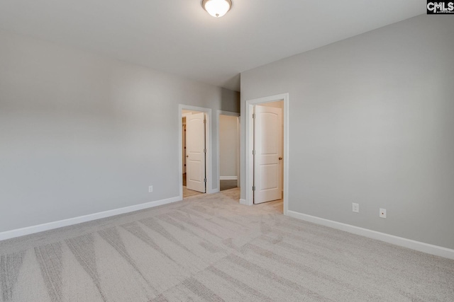 unfurnished bedroom with a spacious closet and light carpet