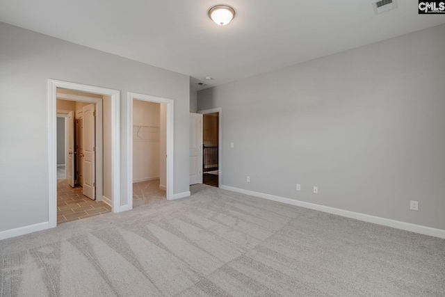 unfurnished bedroom featuring light colored carpet, a closet, and a walk in closet