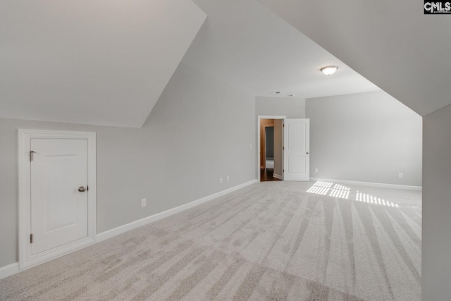 bonus room with vaulted ceiling and light carpet