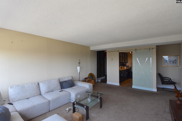 living room with a barn door, carpet, and a textured ceiling