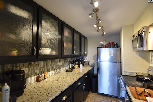 kitchen featuring light stone counters, appliances with stainless steel finishes, tasteful backsplash, and light tile patterned floors