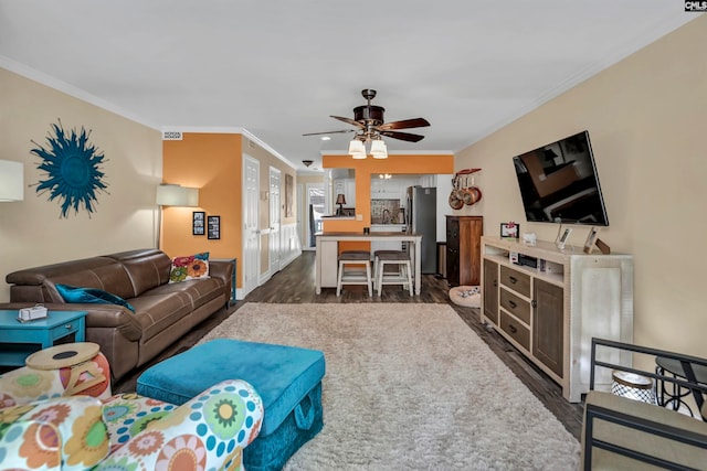 living room featuring dark wood-type flooring, crown molding, and ceiling fan