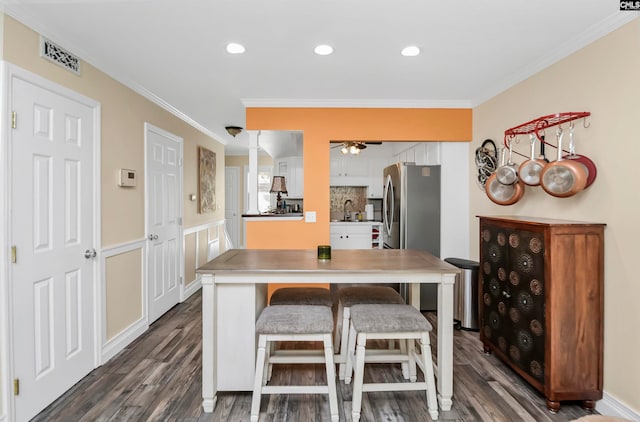 kitchen featuring ceiling fan, dark hardwood / wood-style flooring, white cabinets, ornamental molding, and stainless steel fridge