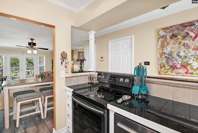 kitchen featuring ceiling fan, black range with electric cooktop, dark hardwood / wood-style floors, ornate columns, and backsplash