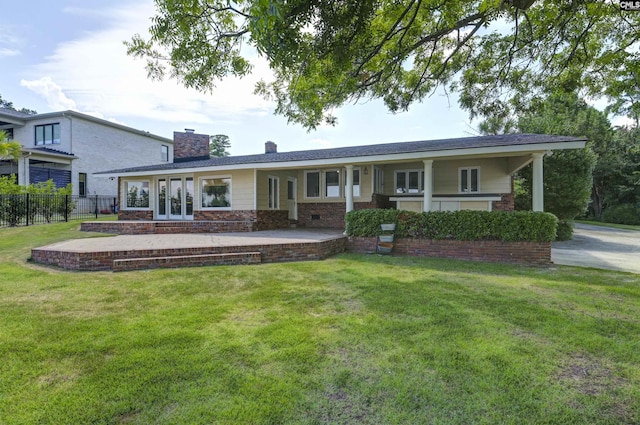 view of front of property with a chimney, fence, french doors, a front lawn, and brick siding