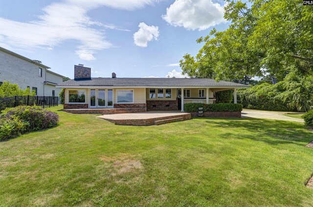 rear view of house featuring a patio, a chimney, crawl space, fence, and a yard