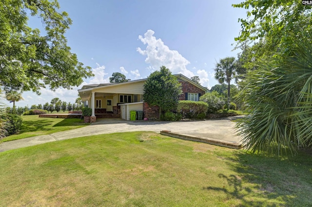 view of front of house with a front lawn, concrete driveway, and brick siding