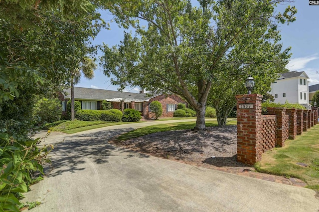 view of front of house with brick siding, driveway, and a front lawn