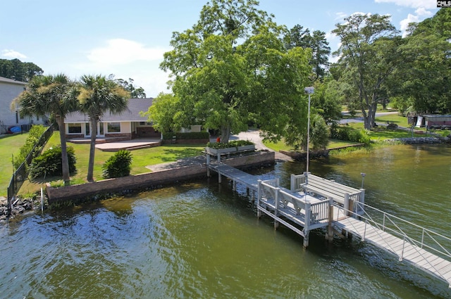 view of dock featuring a patio area, a lawn, and a water view