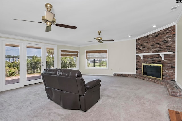 living room with a fireplace, ceiling fan, ornamental molding, brick wall, and light colored carpet