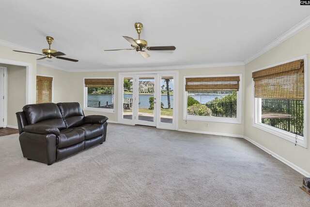 carpeted living room featuring a water view, crown molding, and ceiling fan