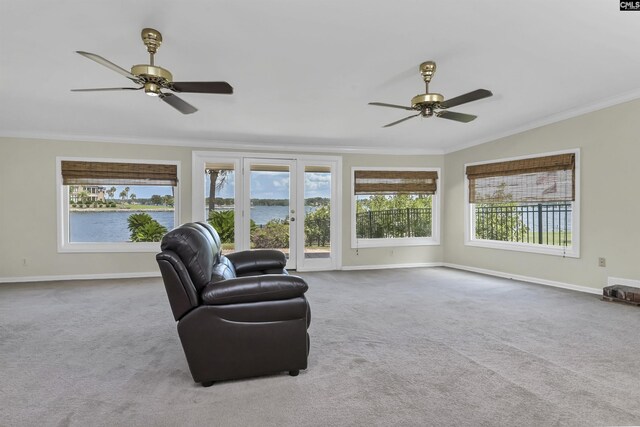 carpeted living room with crown molding, ceiling fan, and a water view