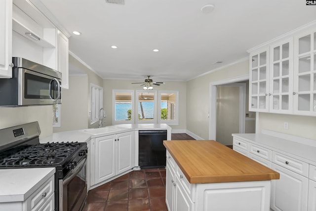 kitchen featuring white cabinets, butcher block countertops, appliances with stainless steel finishes, crown molding, and a sink