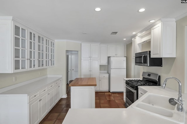 kitchen featuring stainless steel appliances, butcher block countertops, a sink, and white cabinets