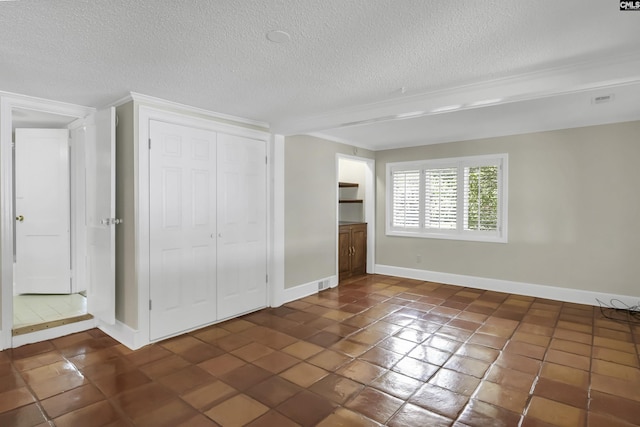 unfurnished bedroom with tile patterned flooring, a textured ceiling, baseboards, and a closet