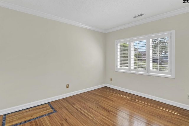 unfurnished room featuring hardwood / wood-style flooring, baseboards, visible vents, and ornamental molding