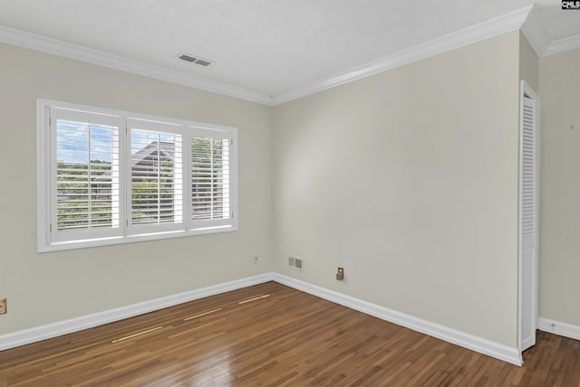 unfurnished room with visible vents, crown molding, baseboards, and wood finished floors