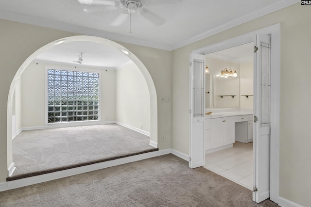 interior space with arched walkways, crown molding, a ceiling fan, light carpet, and baseboards