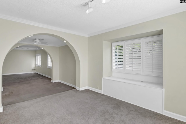 spare room featuring carpet, a textured ceiling, arched walkways, and a ceiling fan