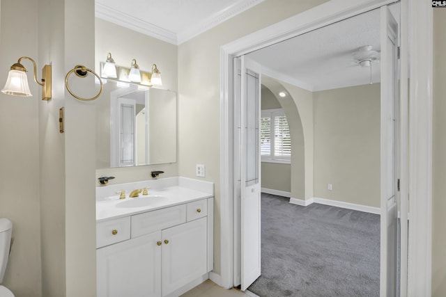 bathroom featuring toilet, crown molding, vanity, and baseboards