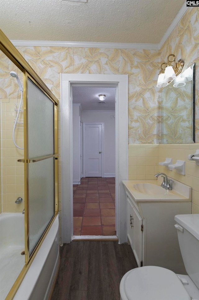 full bathroom featuring vanity, bath / shower combo with glass door, hardwood / wood-style floors, ornamental molding, and toilet