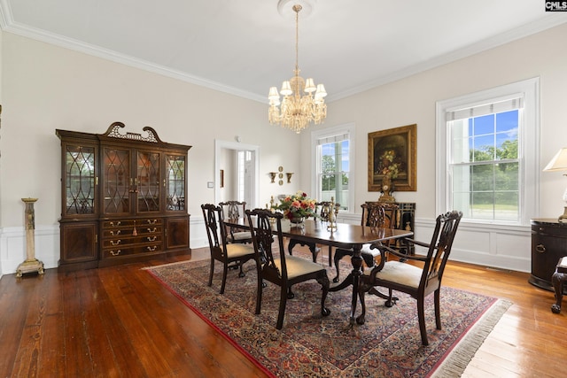 dining area with hardwood / wood-style flooring, ornamental molding, and an inviting chandelier