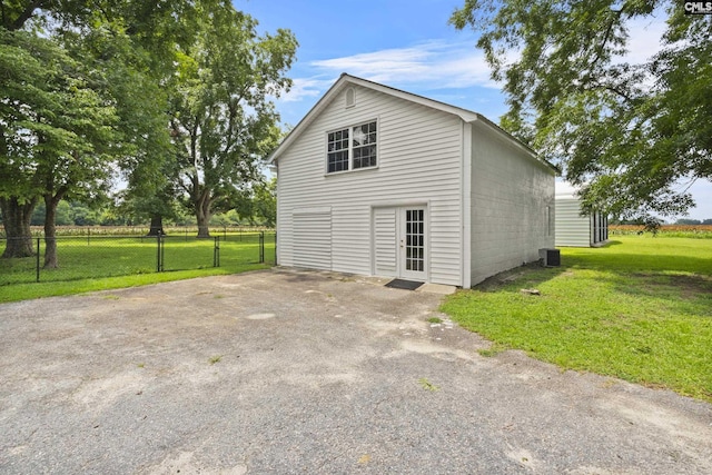 view of side of home with central AC unit and a yard