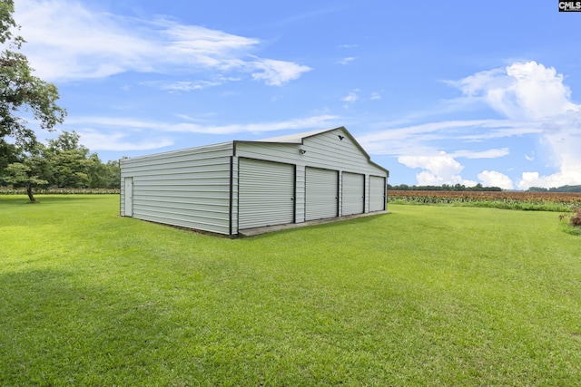 view of outdoor structure with a rural view, a garage, and a lawn