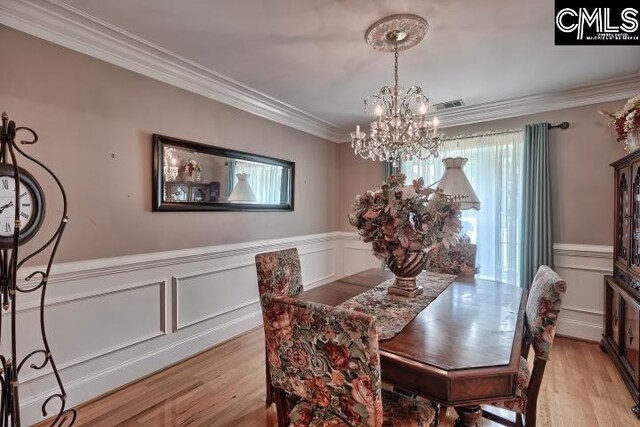 dining area with an inviting chandelier, light hardwood / wood-style floors, and ornamental molding