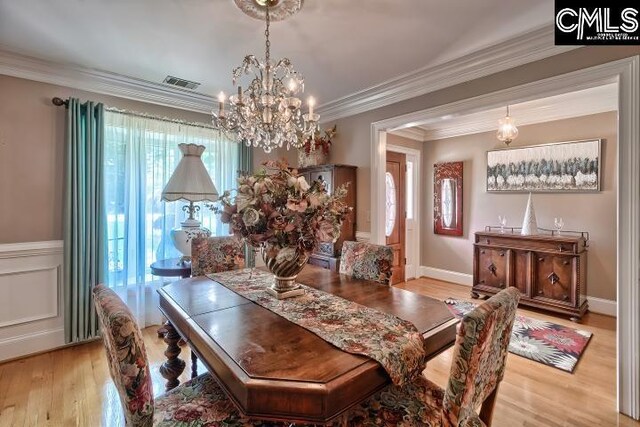 dining space featuring a chandelier, light wood-type flooring, and ornamental molding