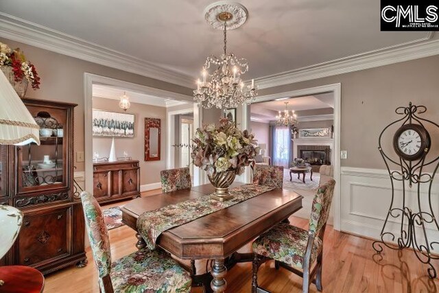 dining area featuring an inviting chandelier, light wood-type flooring, and ornamental molding