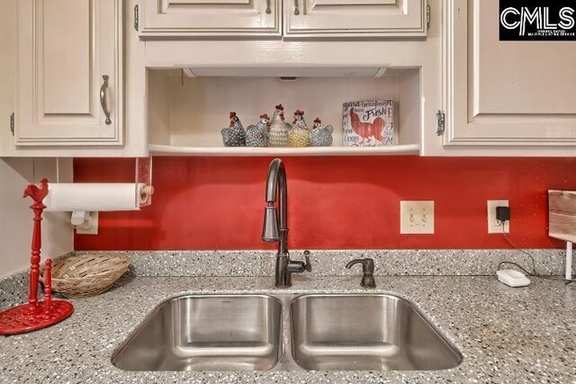 kitchen featuring white cabinets, light stone countertops, and sink