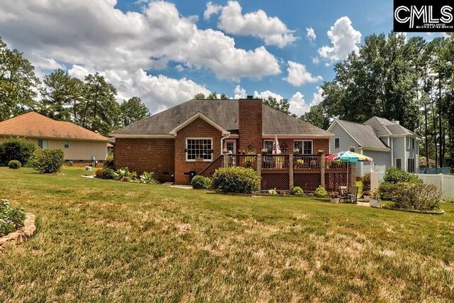 rear view of property featuring a wooden deck and a yard