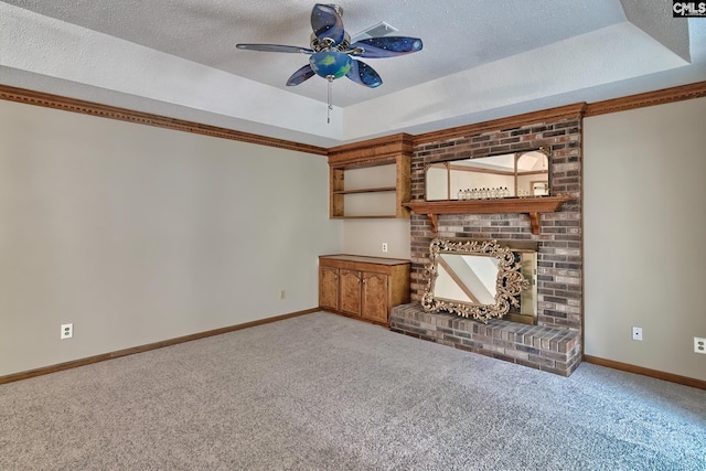 unfurnished living room with a raised ceiling, a brick fireplace, and carpet floors