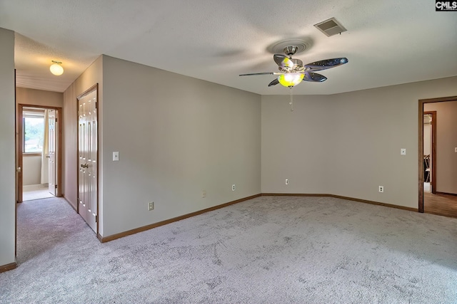 spare room featuring ceiling fan, light colored carpet, and a textured ceiling