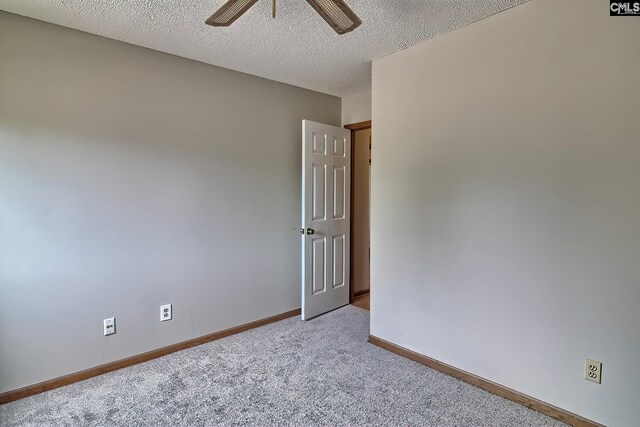 carpeted empty room featuring ceiling fan and a textured ceiling