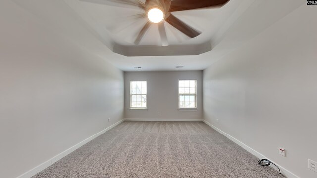 empty room featuring a tray ceiling, carpet, and ceiling fan