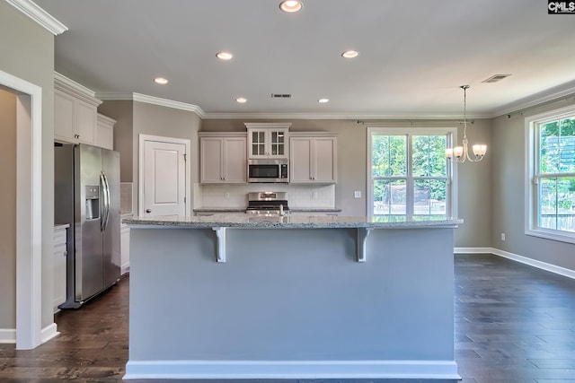 kitchen featuring appliances with stainless steel finishes, a breakfast bar area, pendant lighting, and dark hardwood / wood-style floors