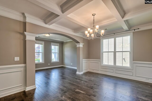 empty room featuring a chandelier, dark hardwood / wood-style floors, ornamental molding, and coffered ceiling