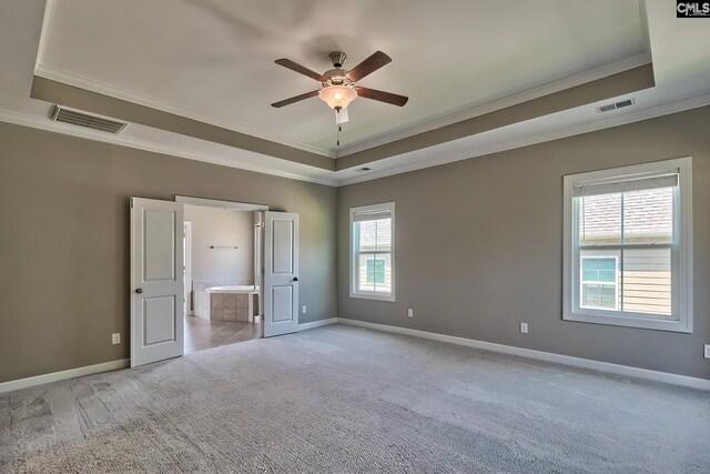 unfurnished bedroom featuring light colored carpet, crown molding, and a tray ceiling