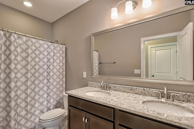 bathroom featuring toilet and dual bowl vanity