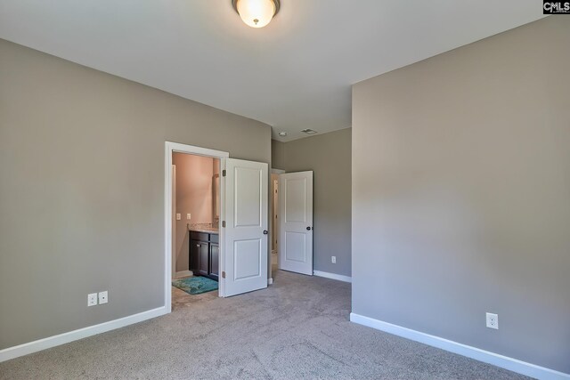 unfurnished bedroom with light carpet and ensuite bathroom